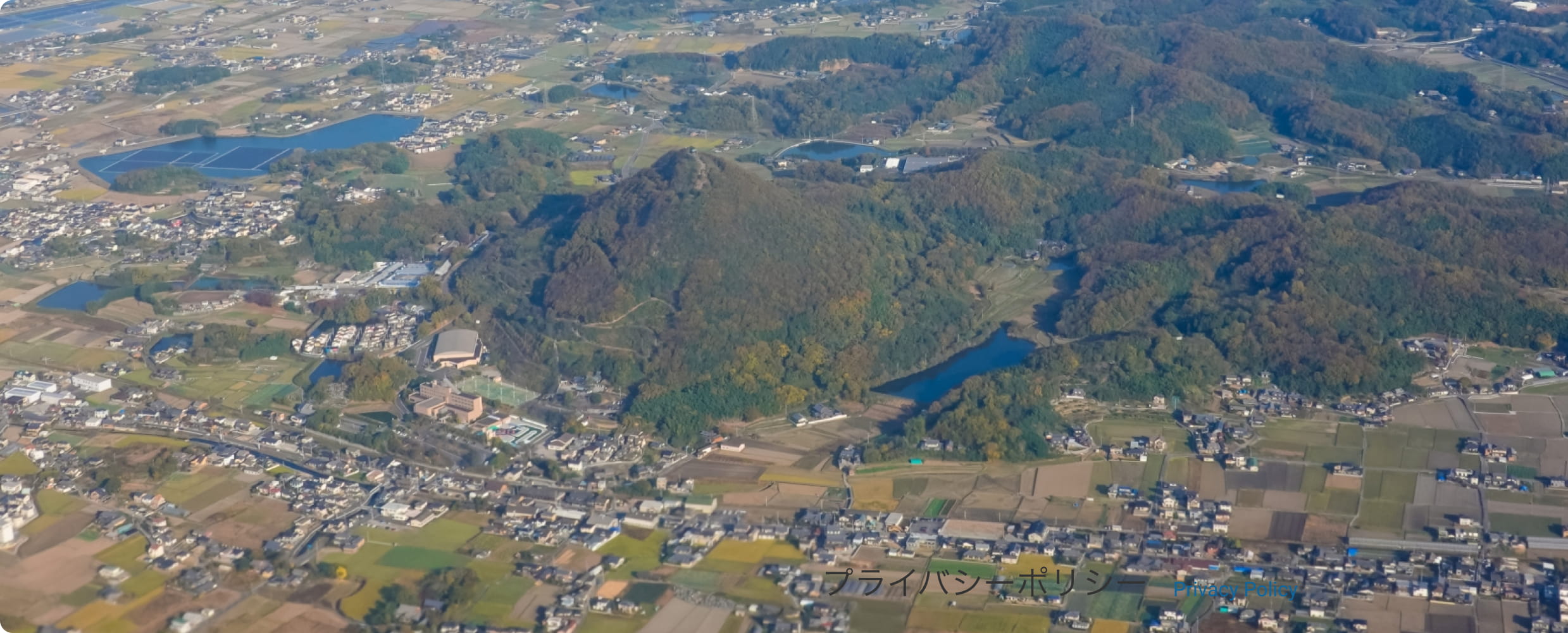 解体現場で多数の重機の前で従業員が右手を突き上げて上を向いている様子